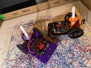 Close-up of drawing robots creating pen drawings