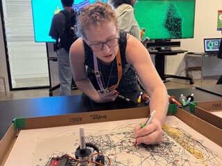 Visitor drawing with the drawing robots at the V&A Digital Design Weekend