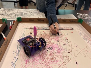 Close-up of a hand drawing alongside a small robot at the V&A Digital Design Weekend